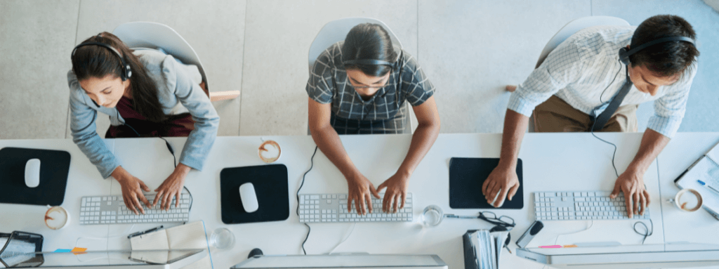 imagem representando colaboradores de call center em suas mesas, em frente ao computador, simulando atendimento ao cliente